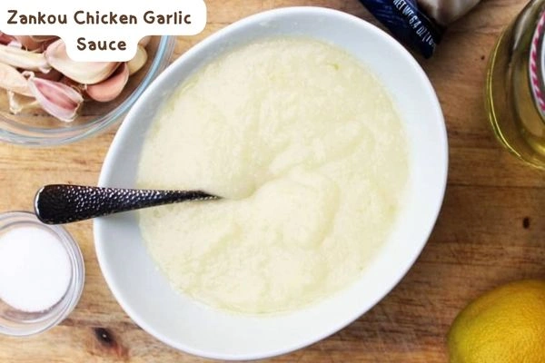 Zankou chicken garlic sauce, a delicate creamy mix of freshly crushed garlic and lemon juice blended into a smooth tahini base, next to pita bread and fresh vegetables.