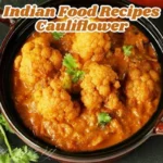 A vibrant bowl of Indian cauliflower curry garnished with fresh coriander leaves, served alongside steamed basmati rice.