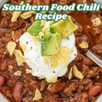 A hearty bowl of Southern-style chilli topped with sour cream, diced avocado, and crushed tortilla chips, served with a silver spoon.