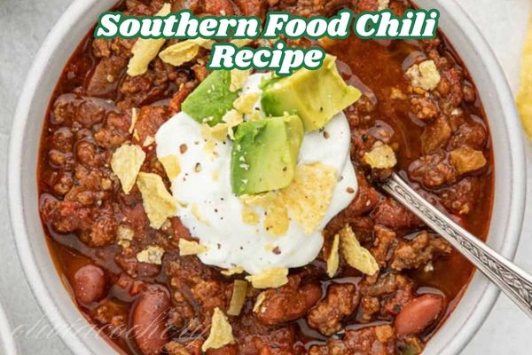 A hearty bowl of Southern-style chilli topped with sour cream, diced avocado, and crushed tortilla chips, served with a silver spoon.